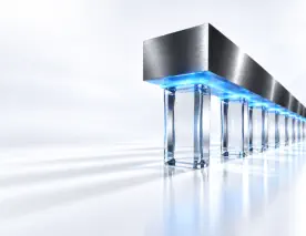 When Ransomware Becomes a Standing Operational Pressure is represented by a premium 3D conceptual engineering render set against a pristine, bright white background. On the right side of the frame, a sophisticated architectural matrix of vertical pillars made of clear sapphire glass is shown. A massive, polished dark steel distribution beam rests horizontally across the top of these pillars, exerting a heavy, constant downward force—symbolising standing operational pressure. Beneath the beam, a razor-sharp, horizontal layer of radiant light-blue light acts as a solid buffer plane. This containment layer cleanly absorbs and distributes the weight, preventing the clear glass pillars below from fracturing or shifting. The left two-thirds of the image seamlessly fades into an expansive white negative space with soft, clean shadows for high-contrast dark typography. Elite corporate technology brand aesthetic.