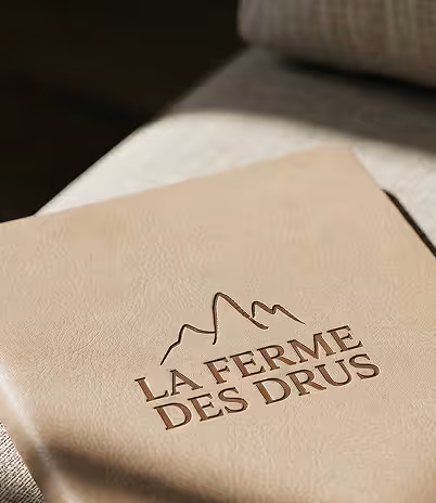 Couverture beige avec le logo embossé de montagnes et le texte La Ferme des Drus, Chamonix-Mont-Blanc, France.