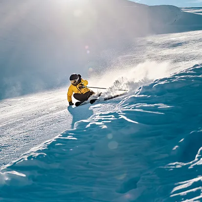 Un skieur en veste jaune glisse sur la neige poudreuse sur une pente ensoleillée, La Ferme des Drus, Chamonix-Mont-Blanc, France.