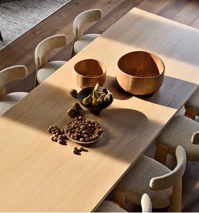 Table en bois clair avec des bols en cuivre et une assiette de fruits secs sous la lumière naturelle, La Ferme des Drus, Chamonix-Mont-Blanc, France.