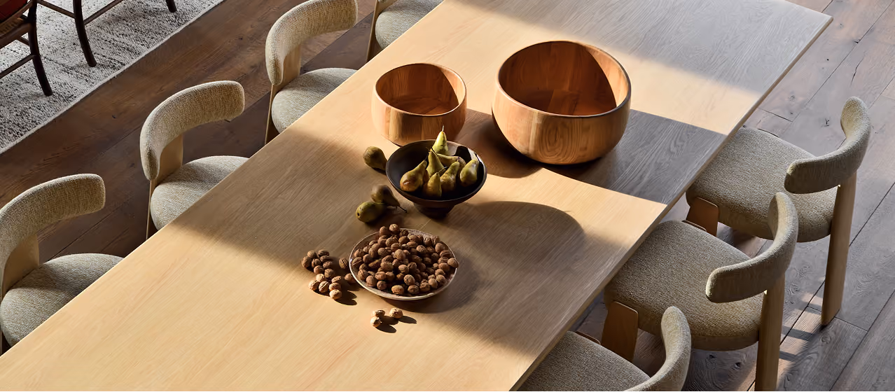 Chaises en tissu autour d'une table en bois clair avec bols et fruits au centre, La Ferme des Drus, Chamonix-Mont-Blanc, France.