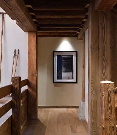 Couloir en bois avec une photo encadrée éclairée sur un mur beige au fond, La Ferme des Drus, Chamonix-Mont-Blanc, France.