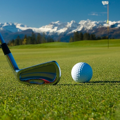 Club de golf et balle sur le gazon avec un drapeau et des montagnes enneigées en arrière-plan, La Ferme des Drus, Chamonix-Mont-Blanc, France.