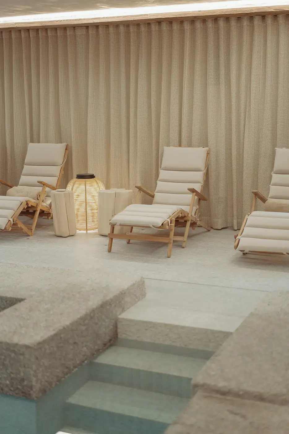 Chaises longues beige près d'une piscine avec une lampe éclairée et un rideau beige en arrière-plan, La Ferme des Drus, Chamonix-Mont-Blanc, France.