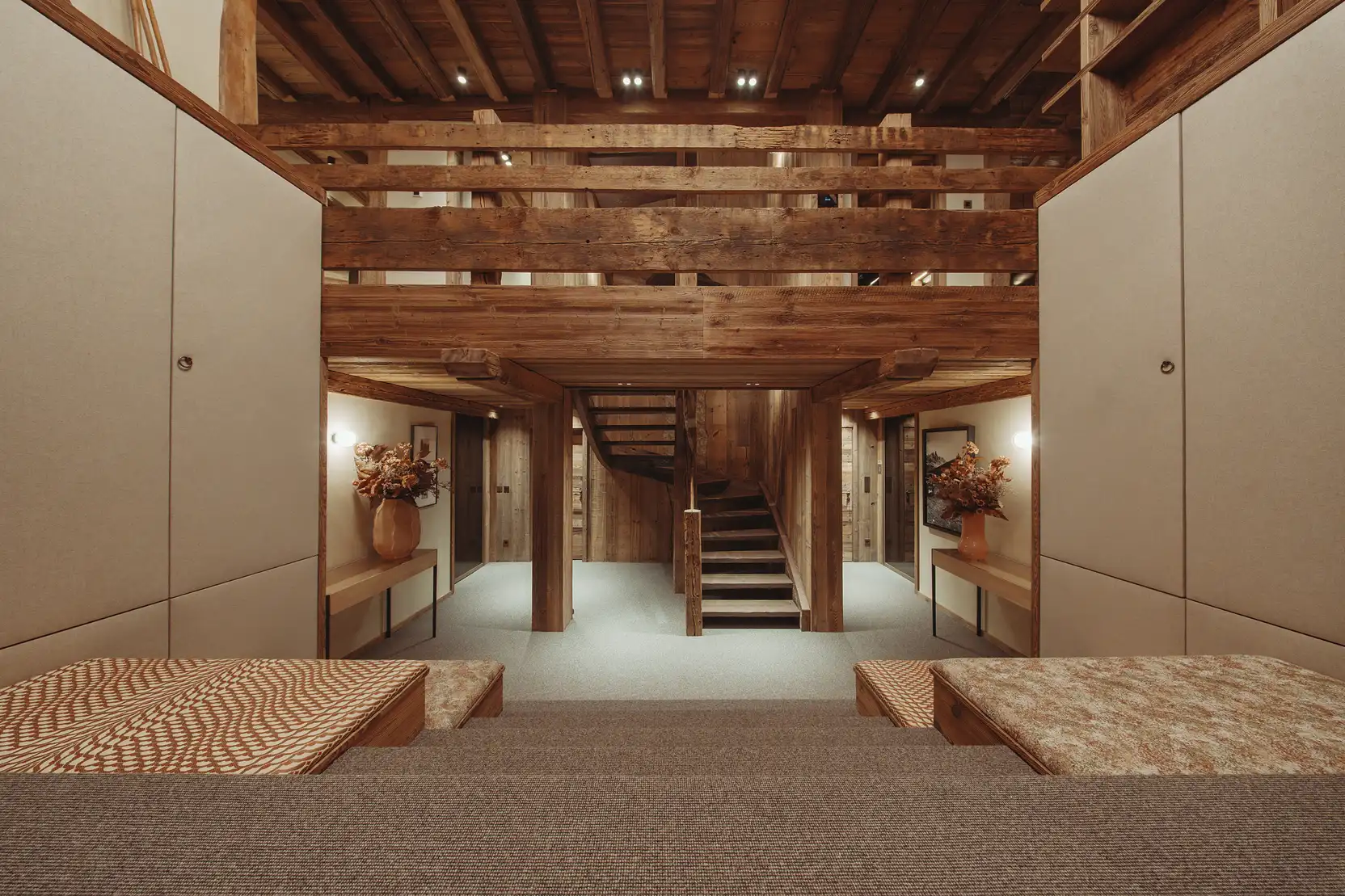 Intérieur en bois chaleureux avec escaliers au centre et bancs rembourrés des deux côtés, La Ferme des Drus, Chamonix-Mont-Blanc, France.