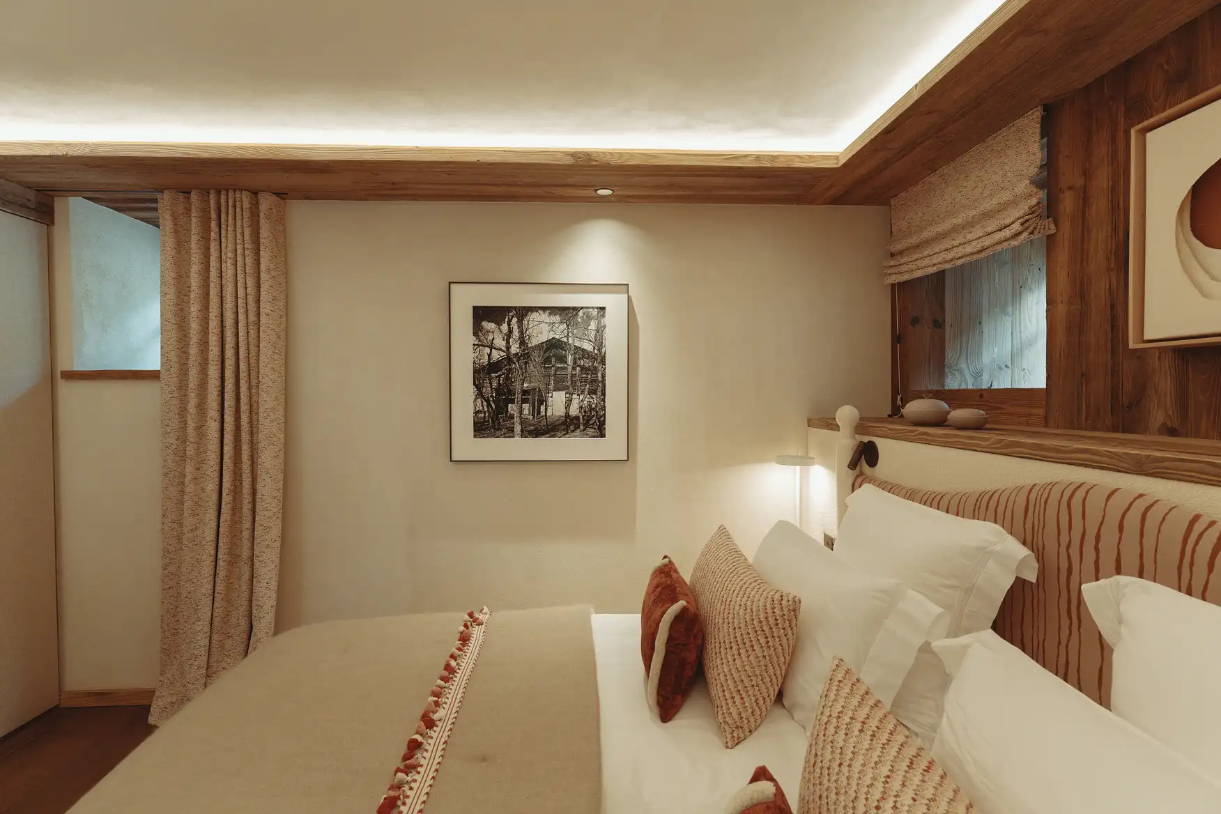 Chambre cosy avec lit beige et blanc, coussins décoratifs, cadre photo et fenêtre avec rideau, La Ferme des Drus, Chamonix-Mont-Blanc, France.