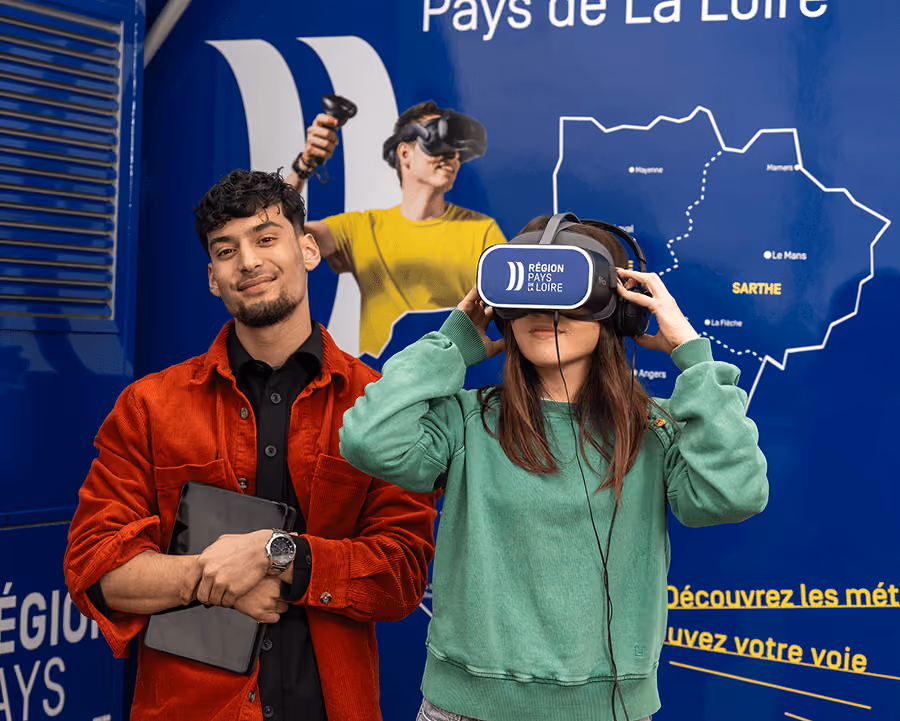Deux jeunes testent un casque de réalité virtuelle à bord du bus Orientibus, devant une carte de la Sarthe