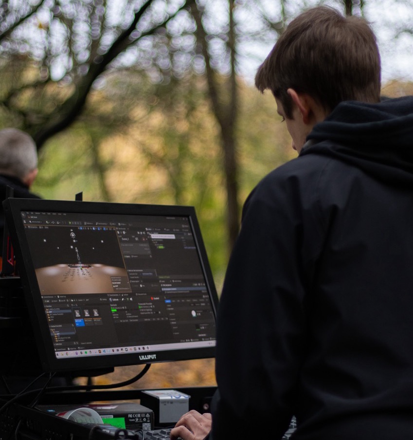 Crew member checking 3D tracking software on a monitor during a forest location shoot