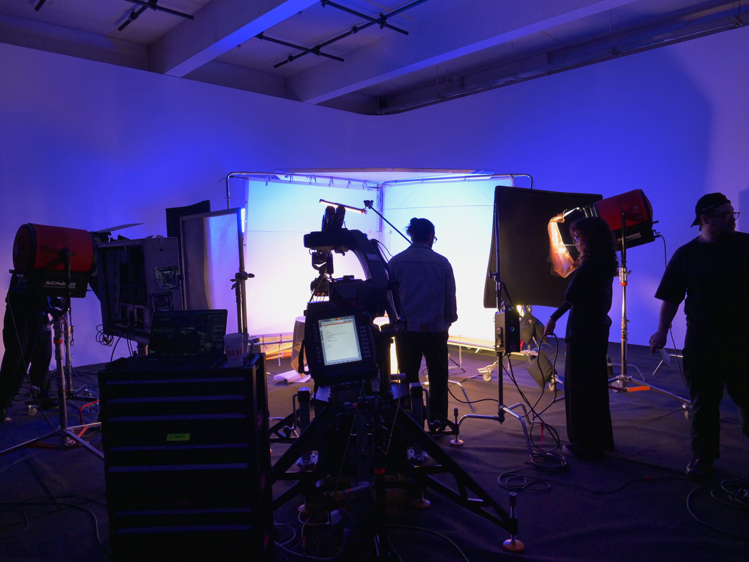 Camera and lighting setup on a blue lit studio stage during a shoot