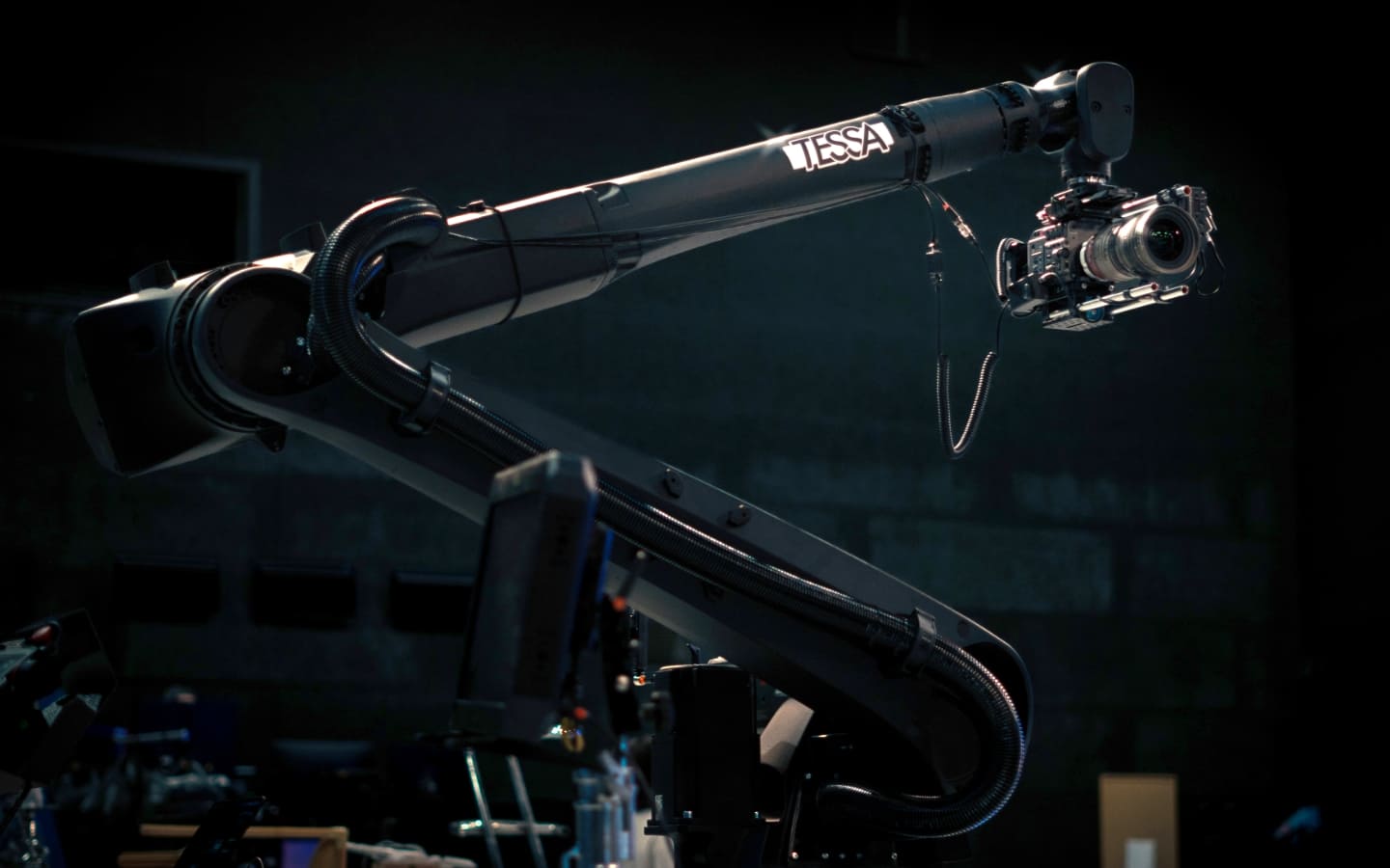 TESSA motion control robotic arm holding a cinema camera in a dark filming studio