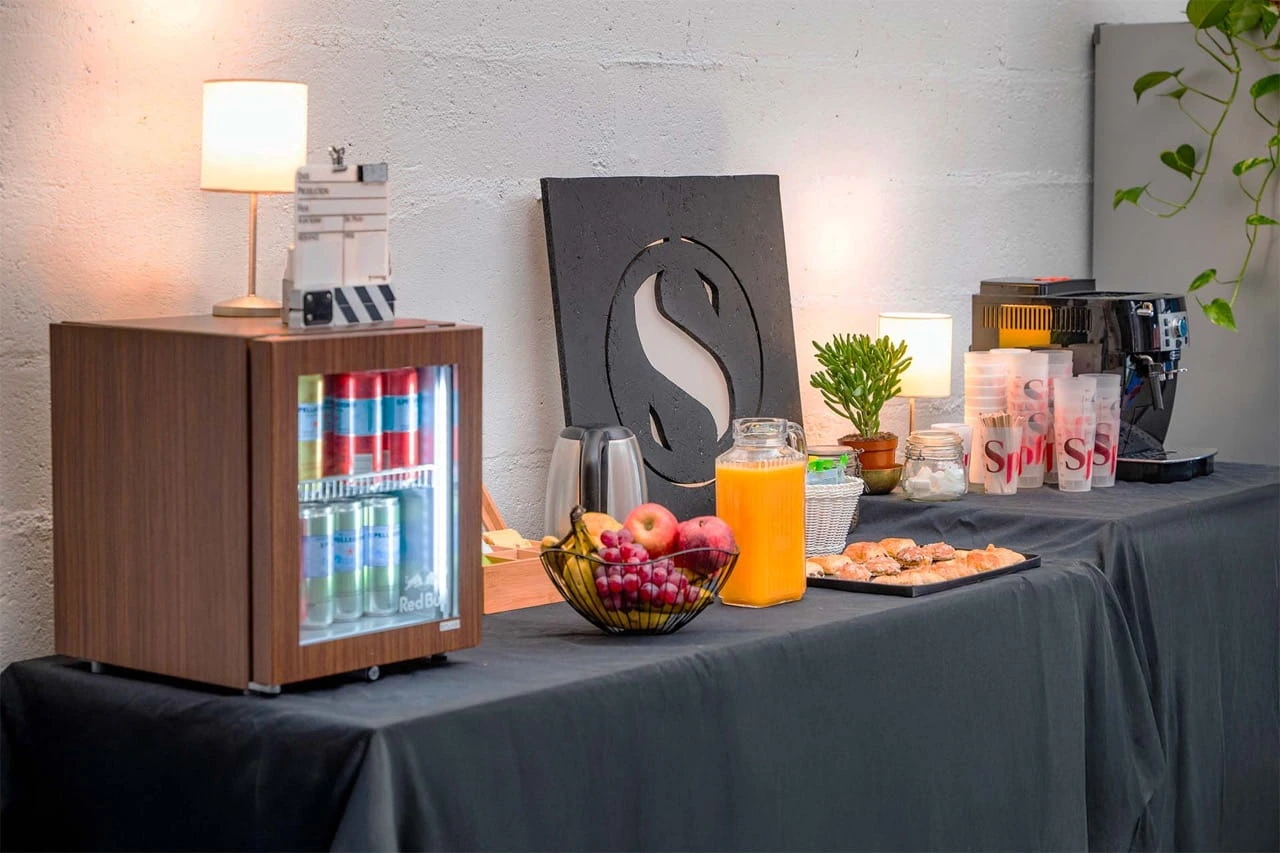 Craft services table with drinks fridge, coffee machine and snacks at Spline studios