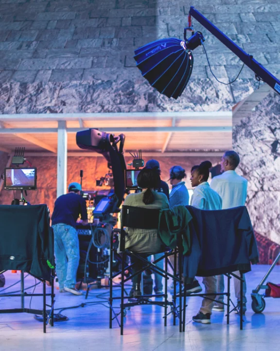 Film crew on an advertising set with a motion control robotic arm and overhead lighting rig