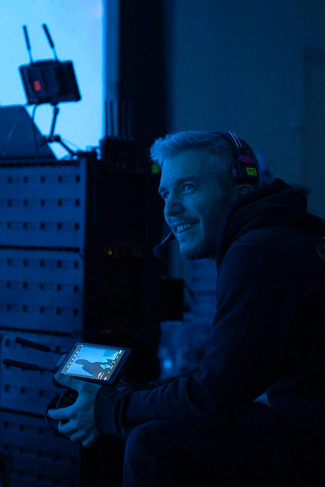 Crew member monitoring a colour reference screen beside a lighting setup on set