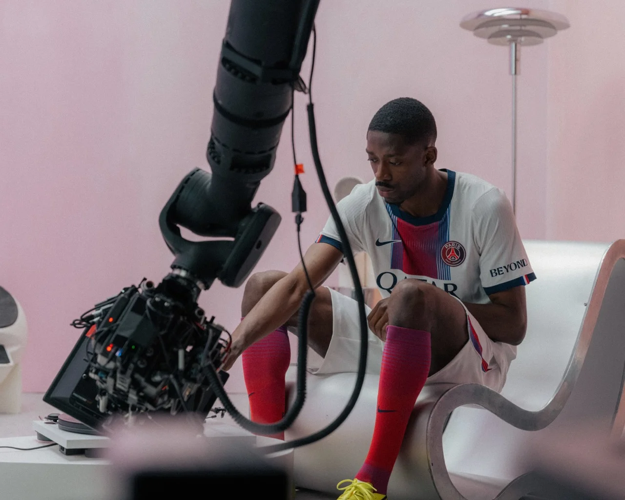 Motion control arm with a cinema camera filming a footballer seated in a pink room