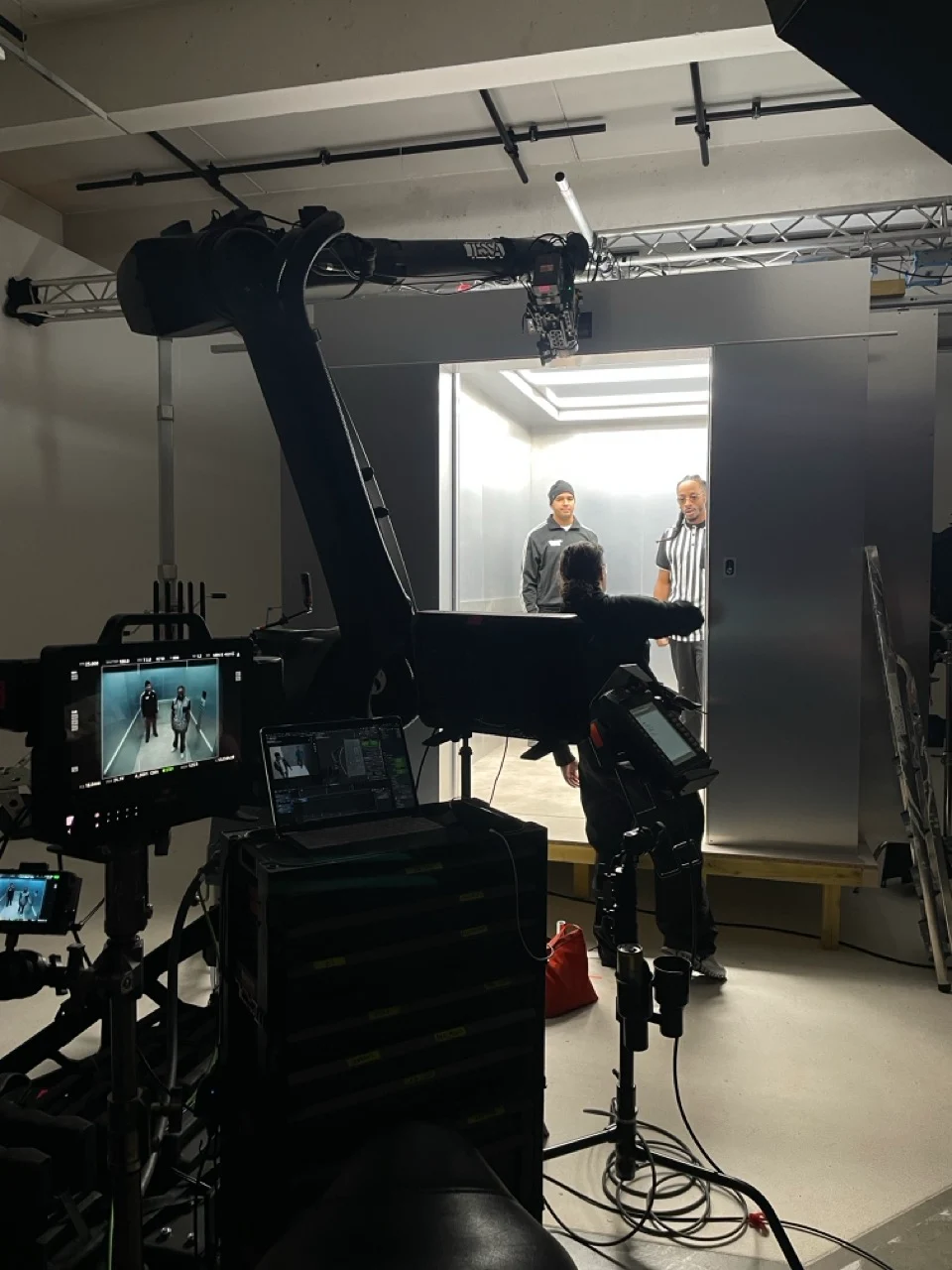 Motion control robotic arm rigged with a cinema camera on a studio set, crew monitoring on video village screens