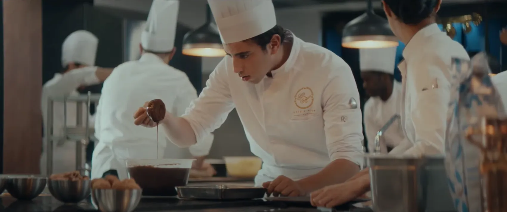 Pastry chef plating a dessert in a professional kitchen, still from À la belle étoile