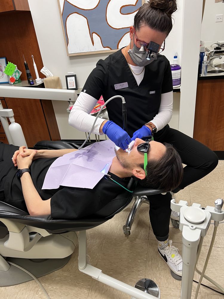 Dental professional providing patient care during a comfortable dental procedure in a modern treatment room with advanced dental equipment
