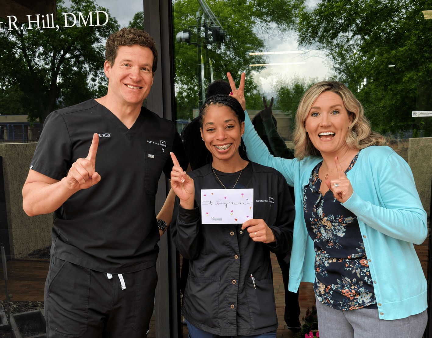 Dentist and team members celebrating together outside the dental office during a community event with smiling staff and patients