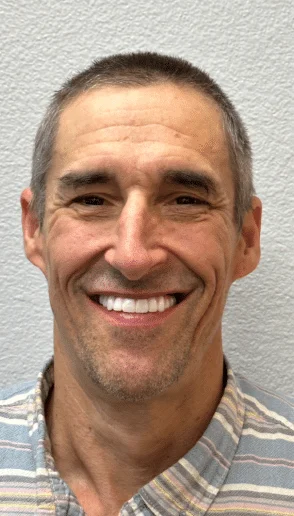 Man smiling after dental treatment with a healthy bright smile against a light gray background