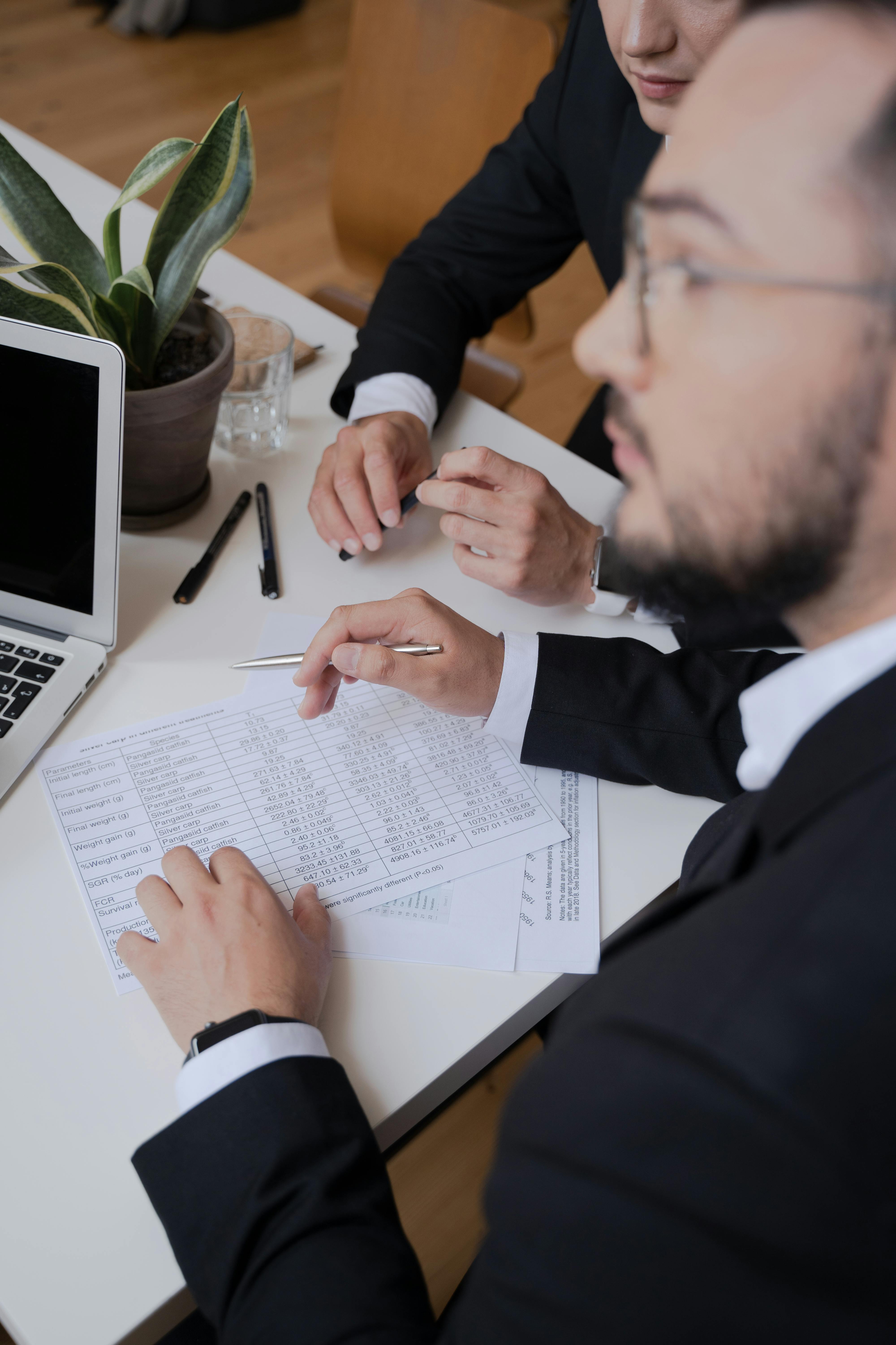 Financial business consultant in a meeting, holding a pen and paper with a spreadsheet. Photo by Pavel Danilyuk.