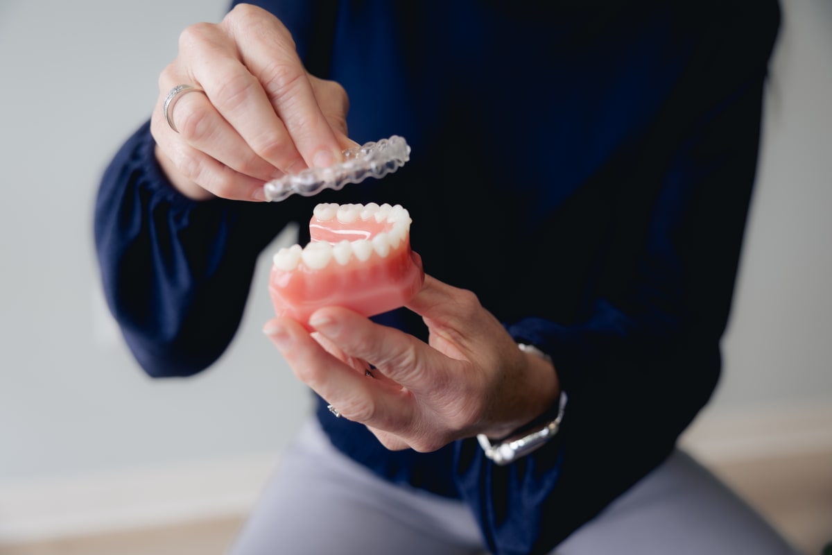 Person holding an Invisalign clear aligner tray between their hands.