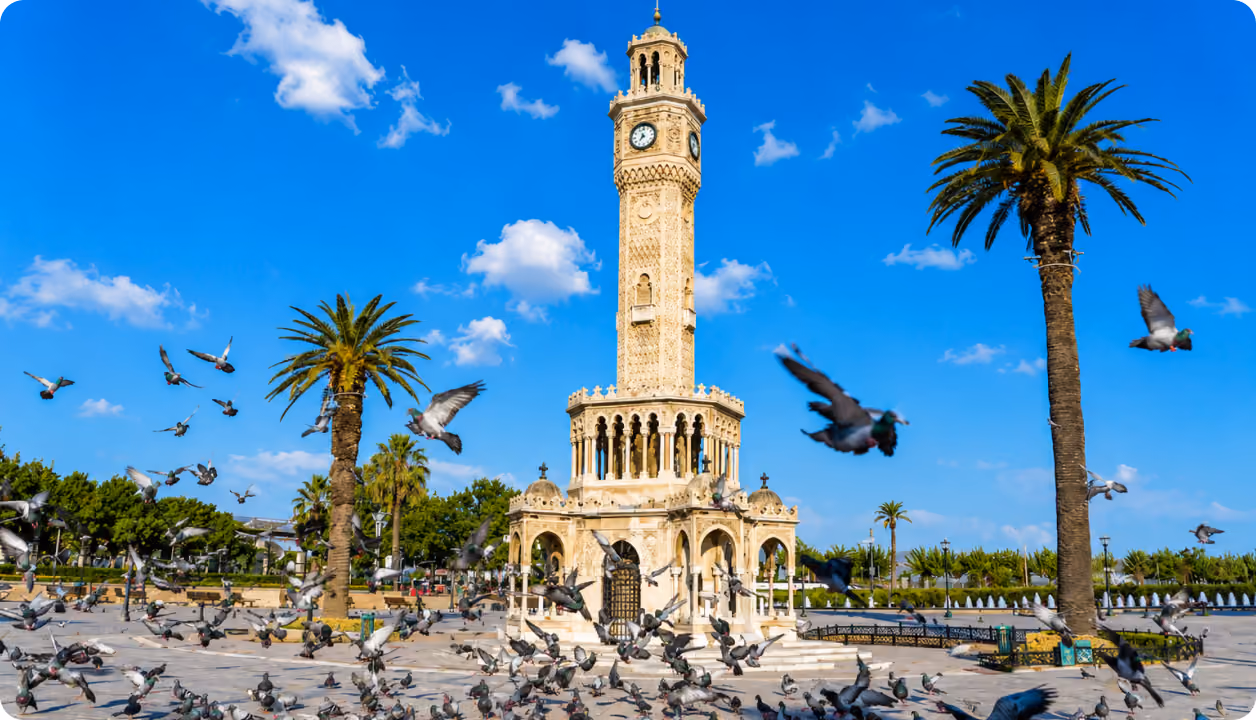 Uhrturm von Izmir mit Palmen und Tauben am Platz