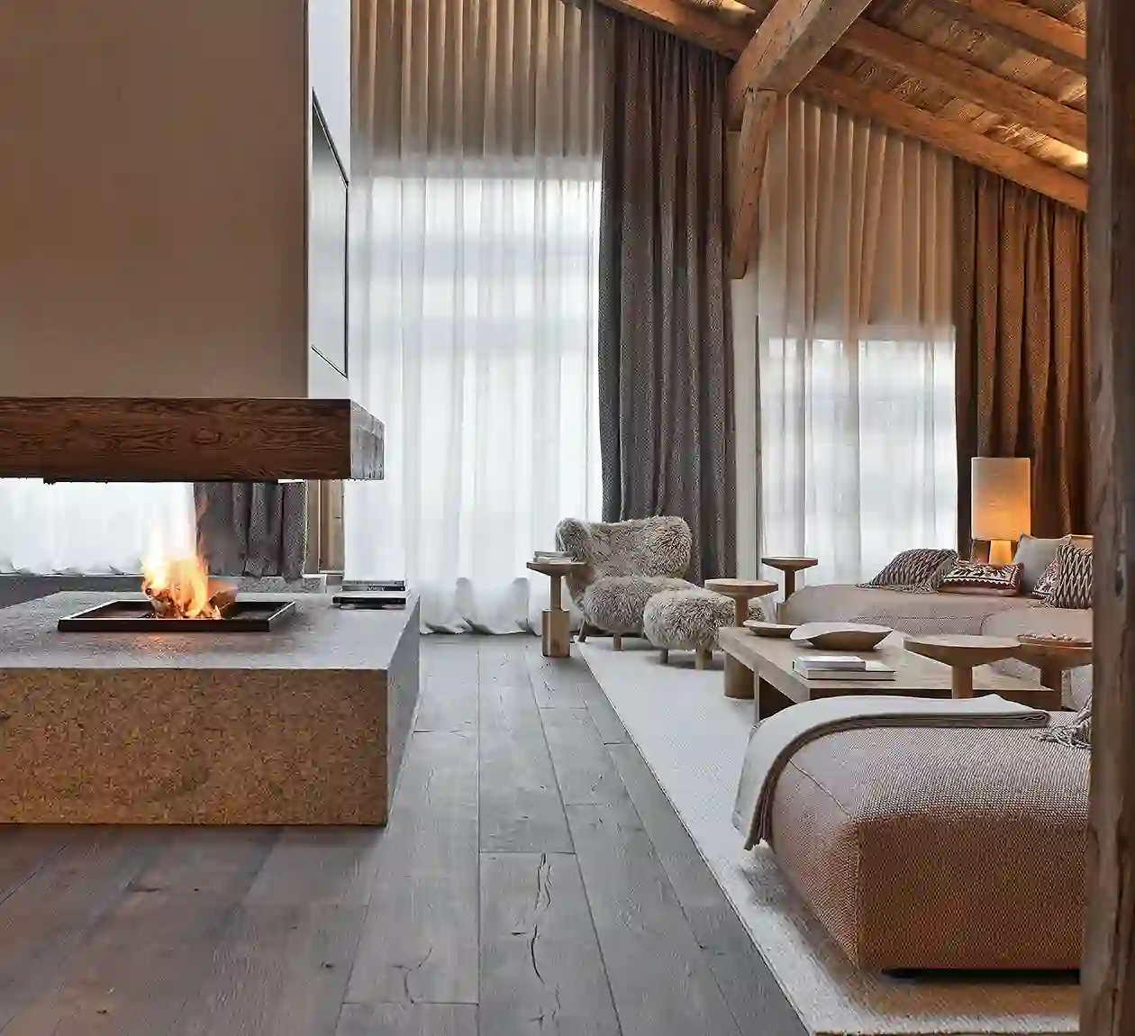 Salon chaleureux et moderne avec une cheminée suspendue et de hauts rideaux, La Ferme des Drus, Chamonix-Mont-Blanc, France.