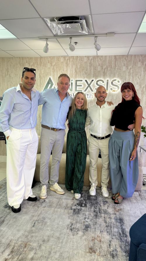 The Nexsis BioHealth team together beneath the clinic sign at their Brickell, Miami location