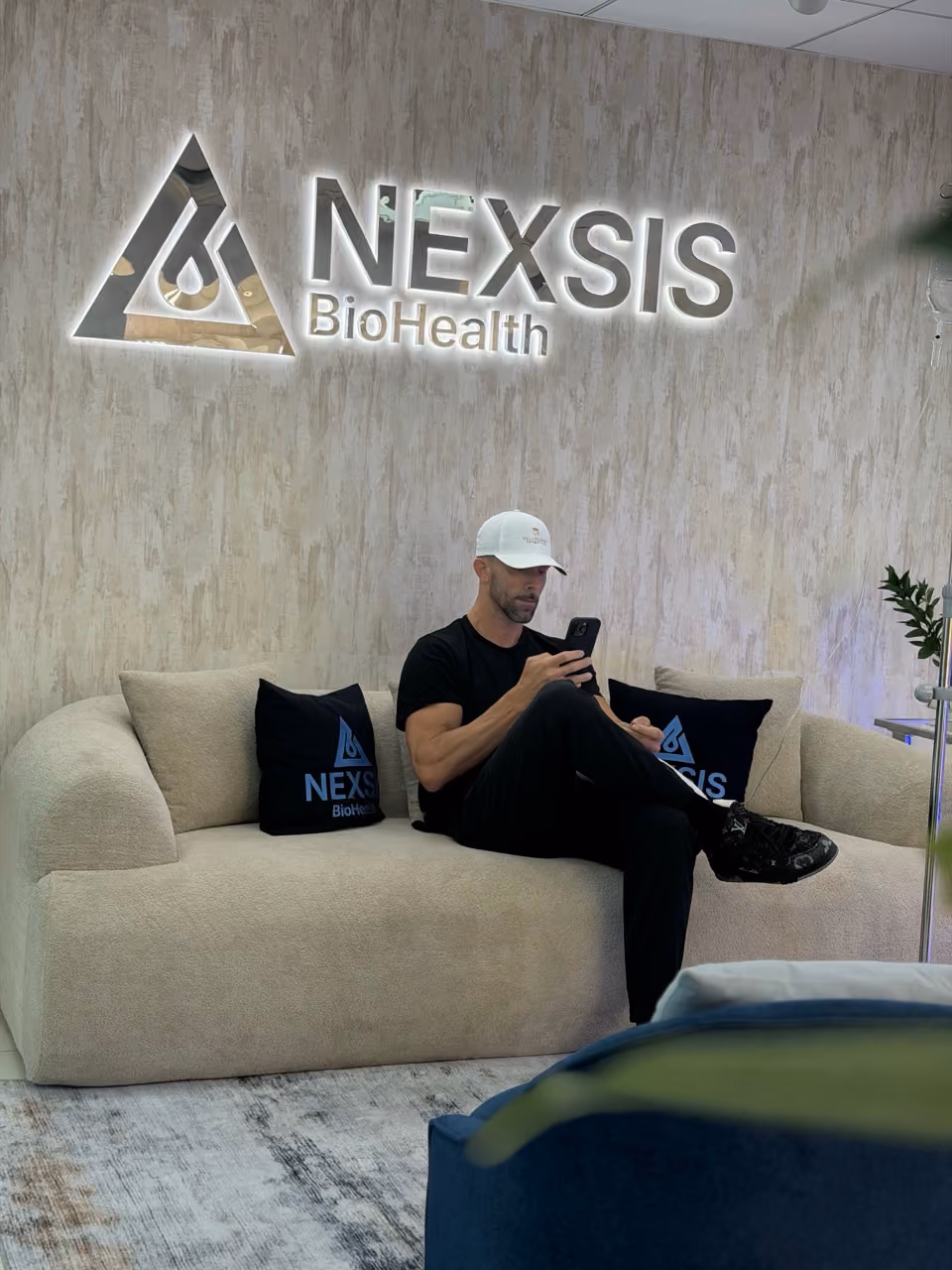 Patient seated on the lobby couch beneath the Nexsis BioHealth sign at the Brickell, Miami clinic