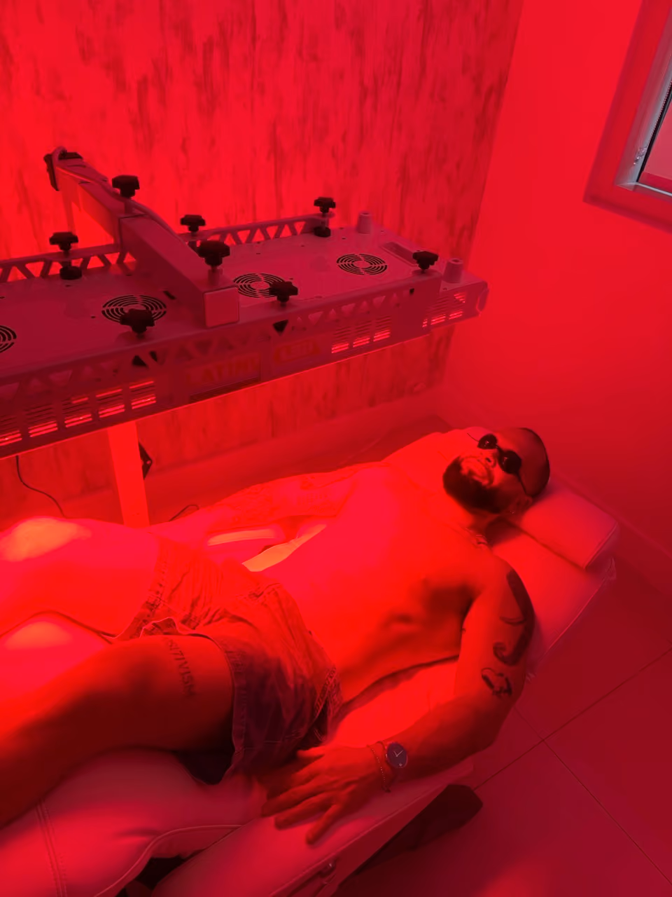 Patient lying under a medical-grade red light therapy panel at the Nexsis BioHealth clinic in Brickell, Miami