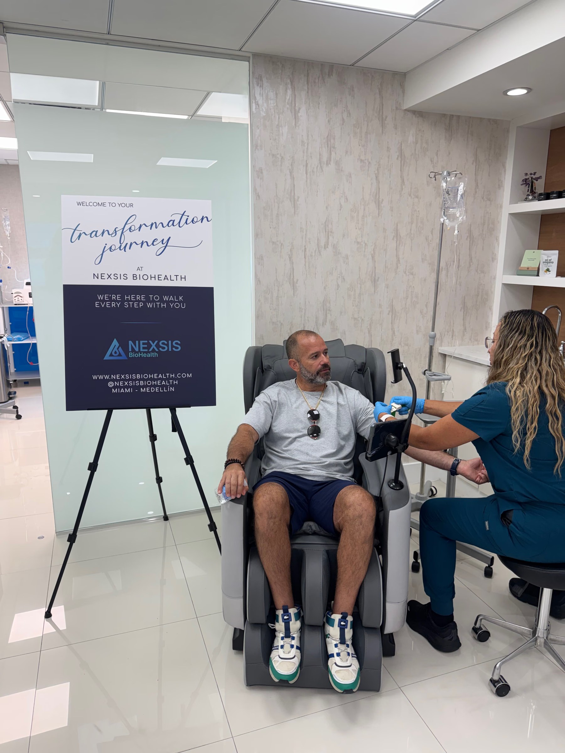 A clinician starting an IV drip for a seated patient at Nexsis BioHealth in Brickell, Miami