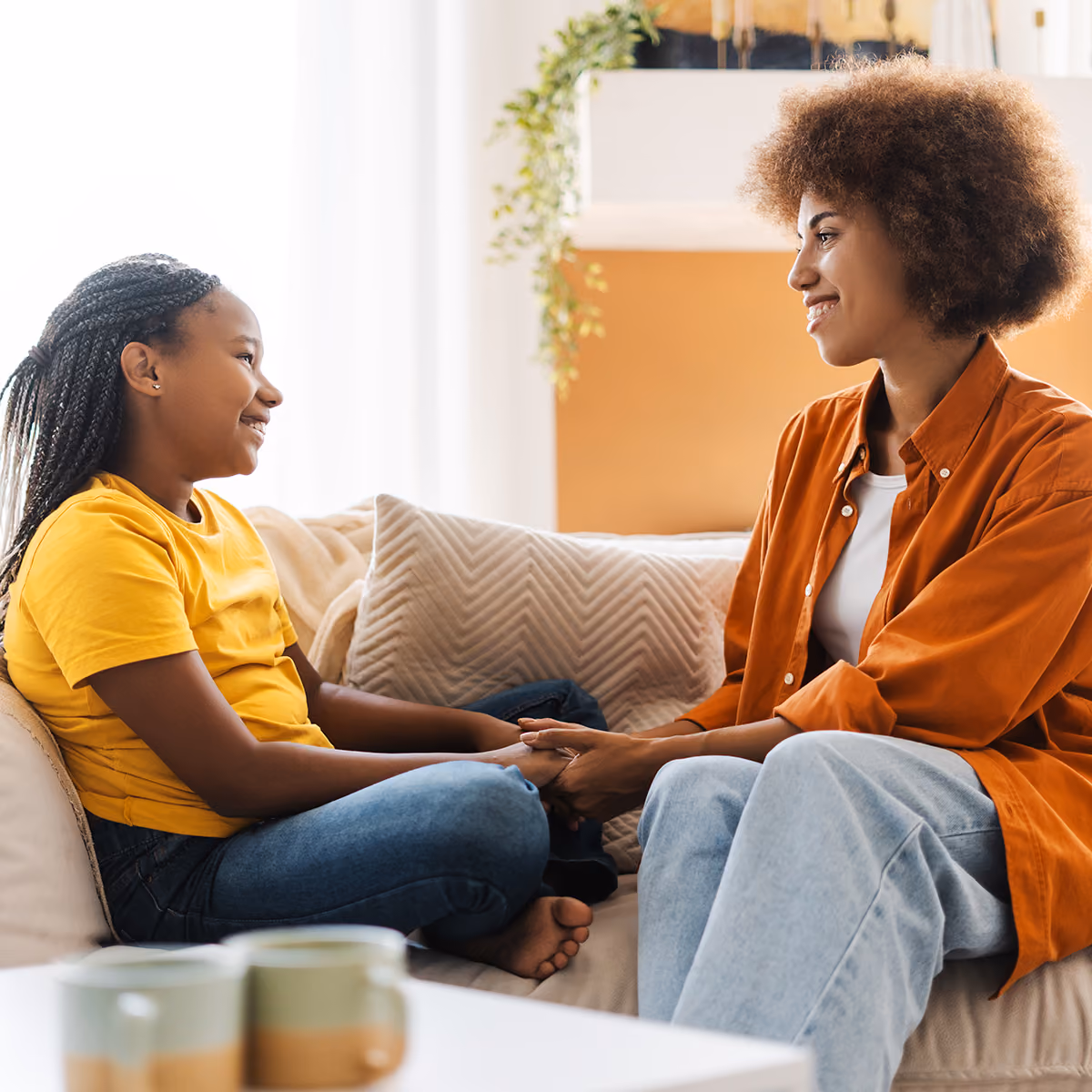 Mom and daughter talking with one another on couch. 