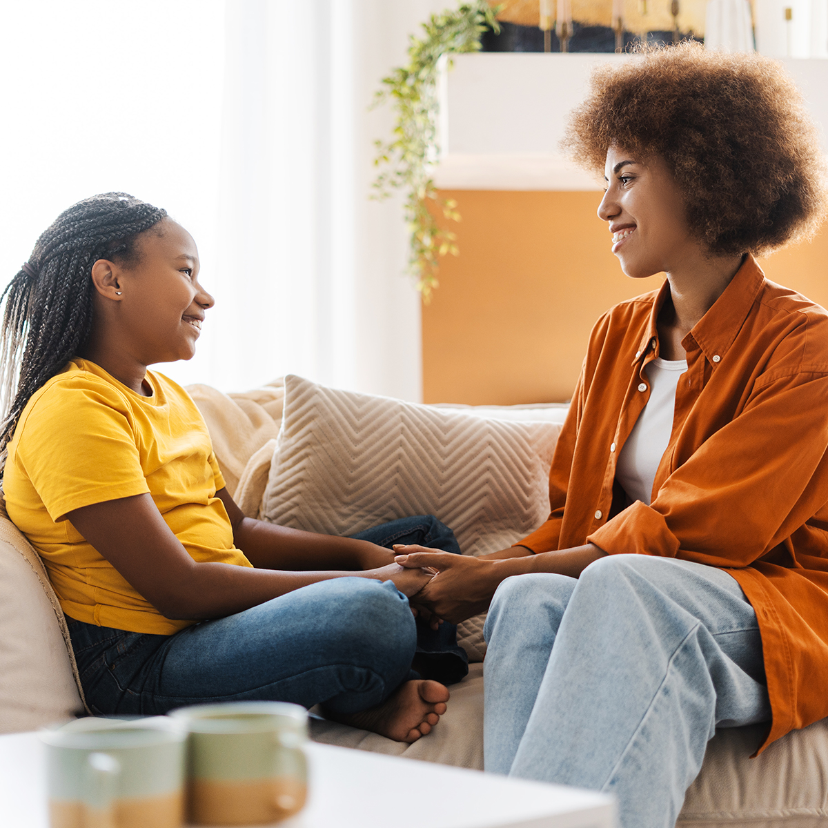 Mom and daughter talking with one another on couch.