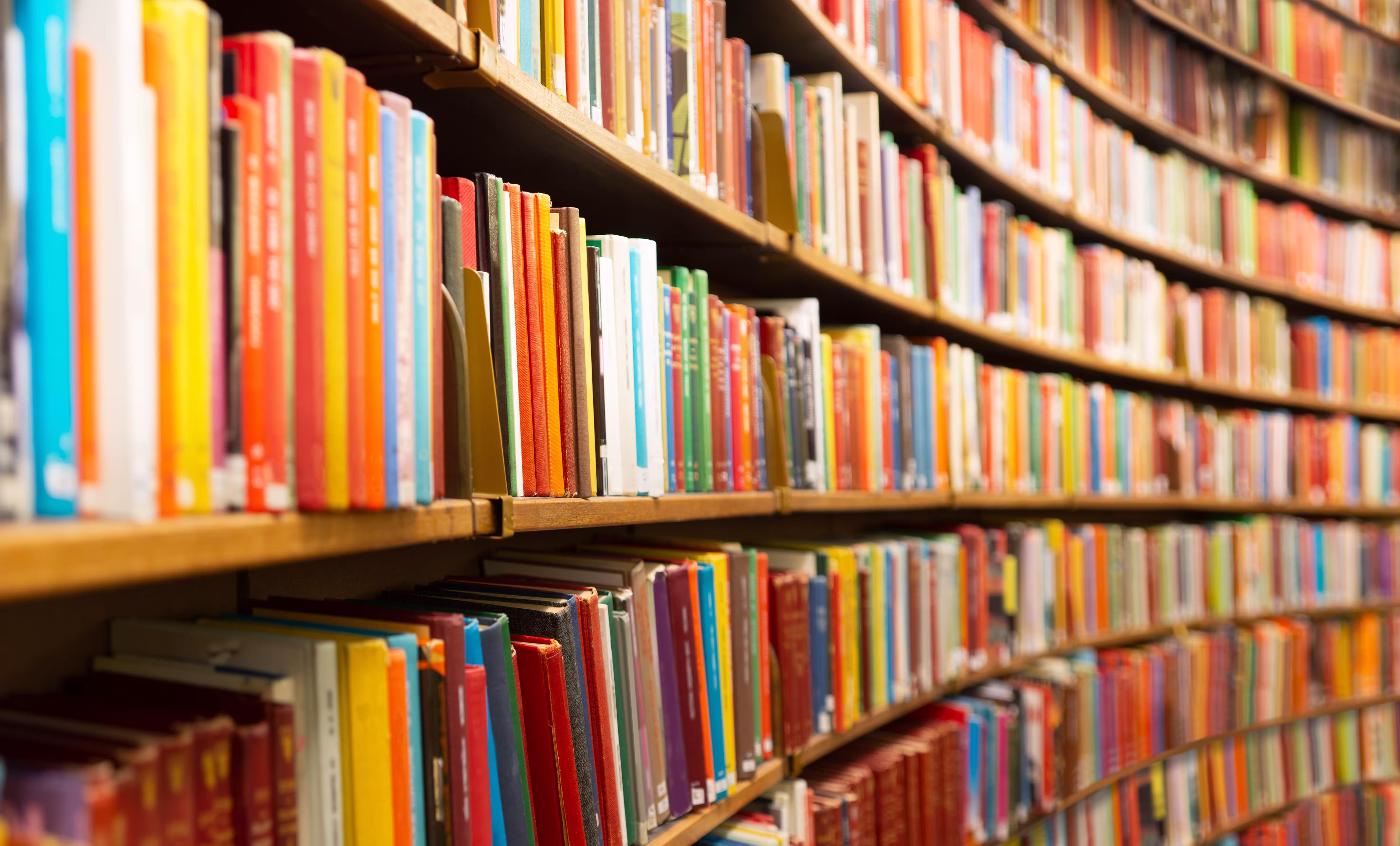 Books lining curved library shelves in an academic library, symbolizing research, scholarship, and learning.