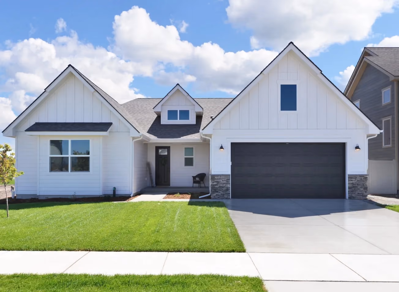 White modern farmhouse with board-and-batten siding and stone accents