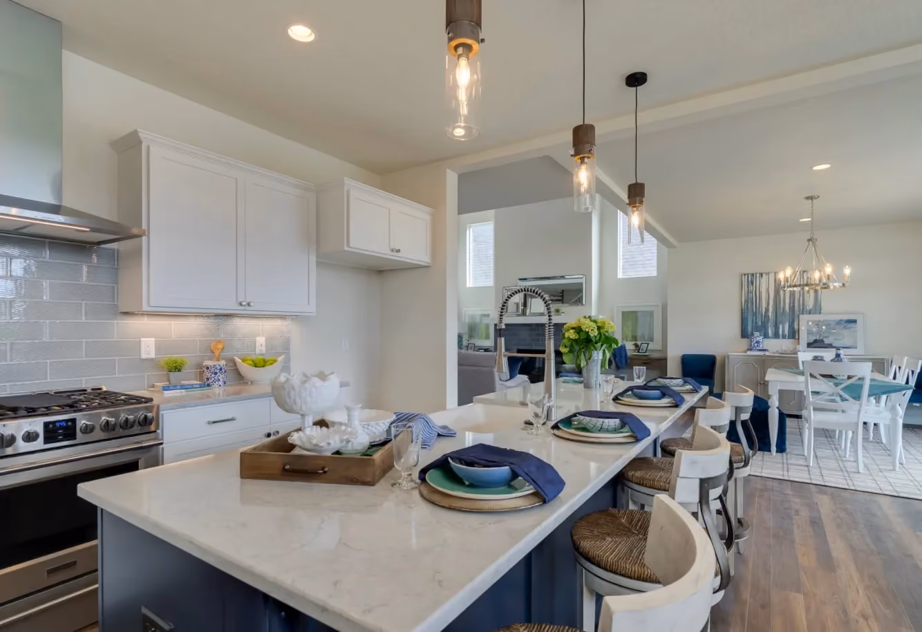 Open-concept kitchen with quartz island, pendant lighting, and dining beyond