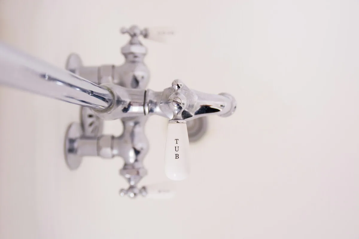 Close-up of a shiny chrome bathtub faucet with a white handle labeled "TUB" against a plain white background.