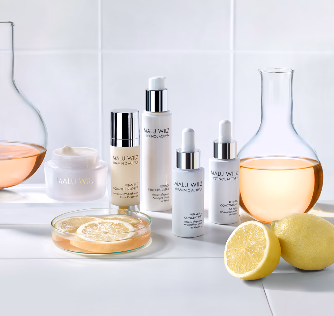 Malu Wilz Pflegeprodukte mit Vitamin C und Retinol mit Zitronenscheiben und Flüssigkeit in Laborflaschen.