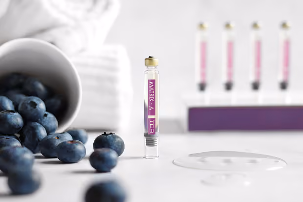 Kosmetikampulle Matrix A Top vor Glas mit Heidelbeeren und Tropfen Serum.