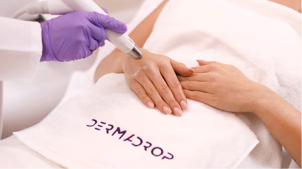 Kosmetikerin behandelt Hand einer Frau mit dem Dermadrop Gerät.