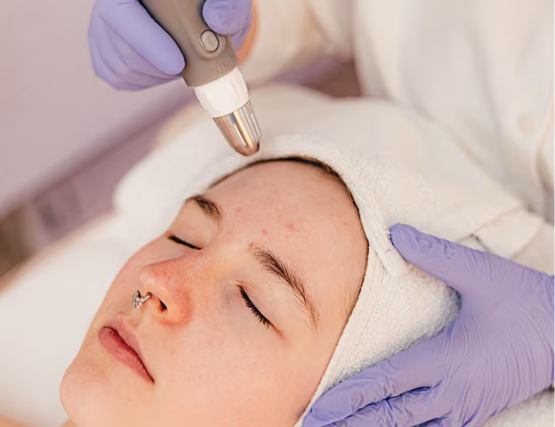 Frau erhält eine Gesichtsbehandlung mit dem Dermadrop, während sie ein Handtuch auf dem Kopf trägt.