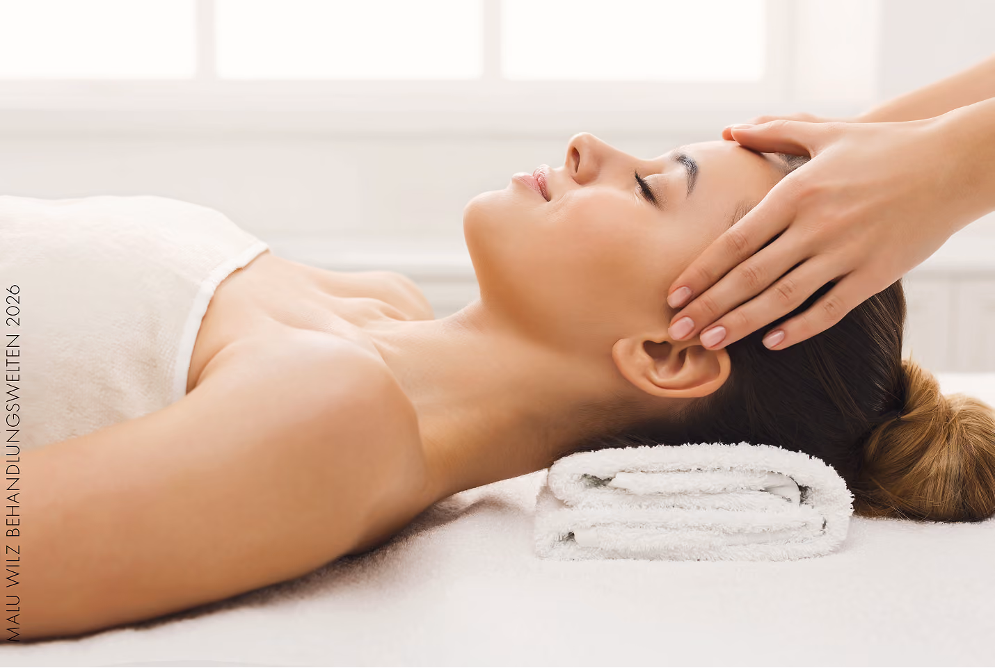 Frau liegt entspannt auf Massagetisch, erhält sanfte Gesichtsmassage mit Händen im Kosmetikstudio.