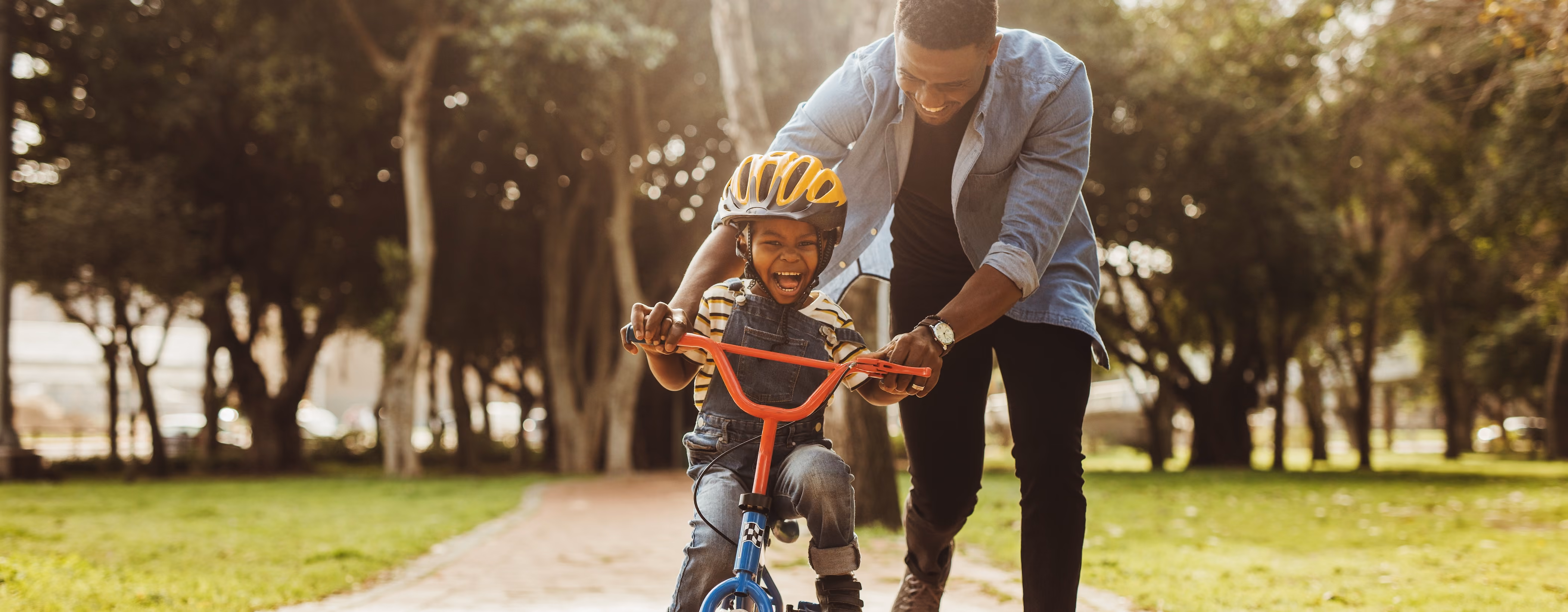 Dad helping some ride his bike stock image