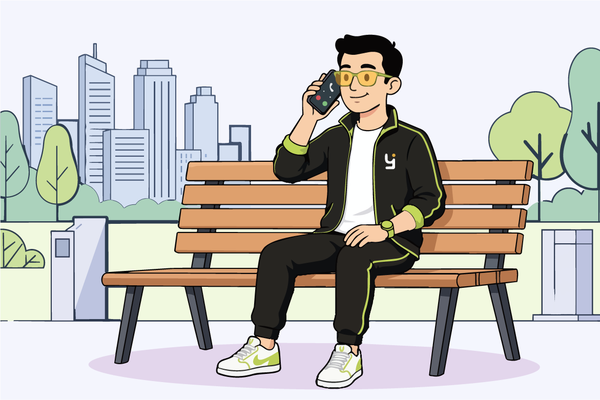 Hombre con gafas amarillas sentado en un banco en un parque hablando por teléfono móvil.