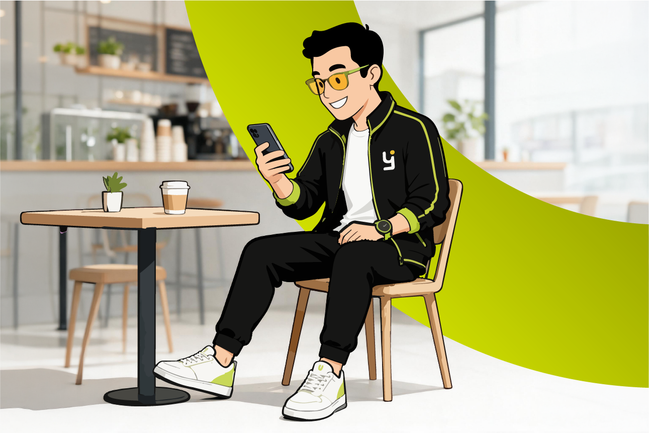 Persona con gafas amarillas sentada en una silla, usando un móvil en una cafetería moderna.