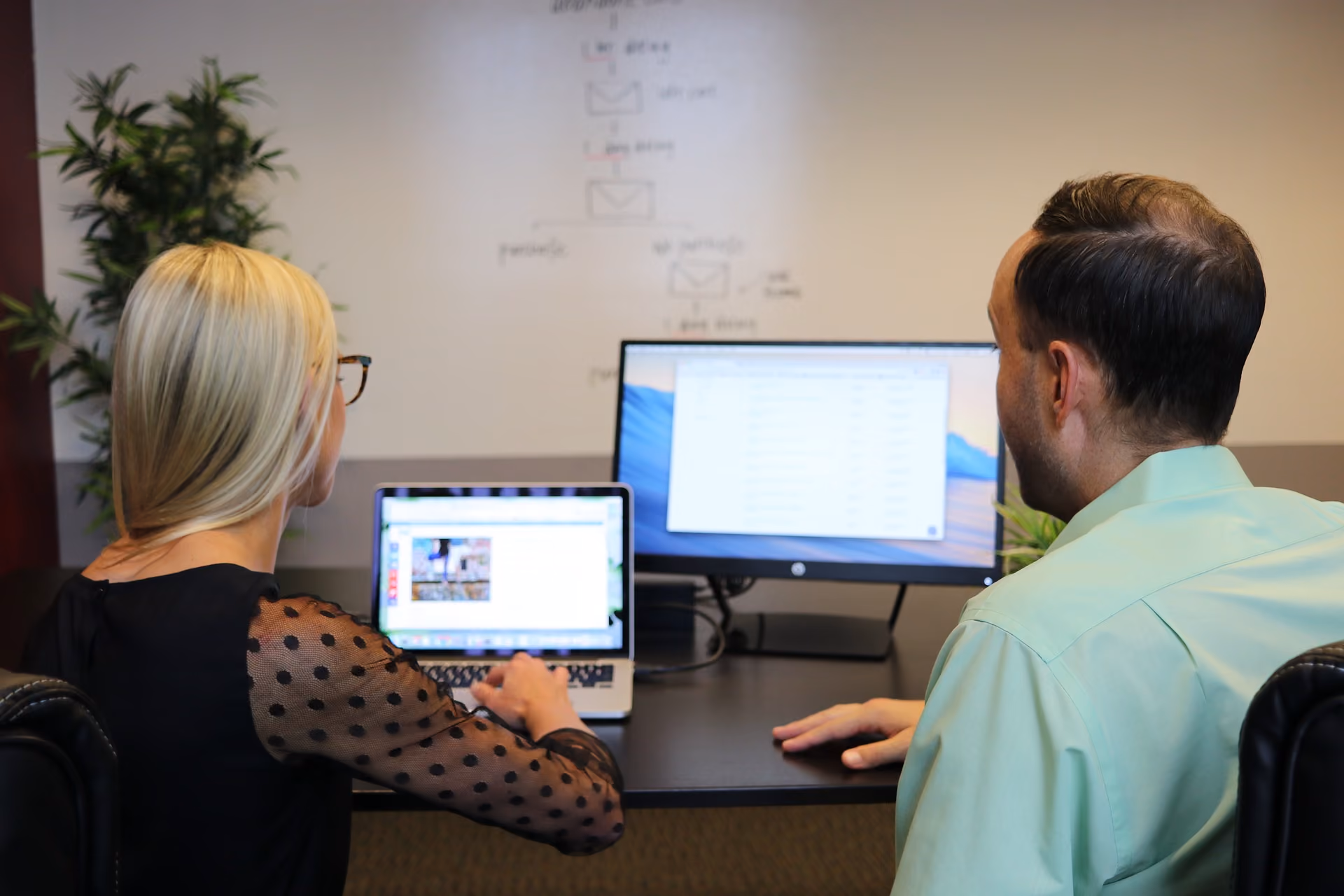 Two team members reviewing a website design on a laptop and a monitor