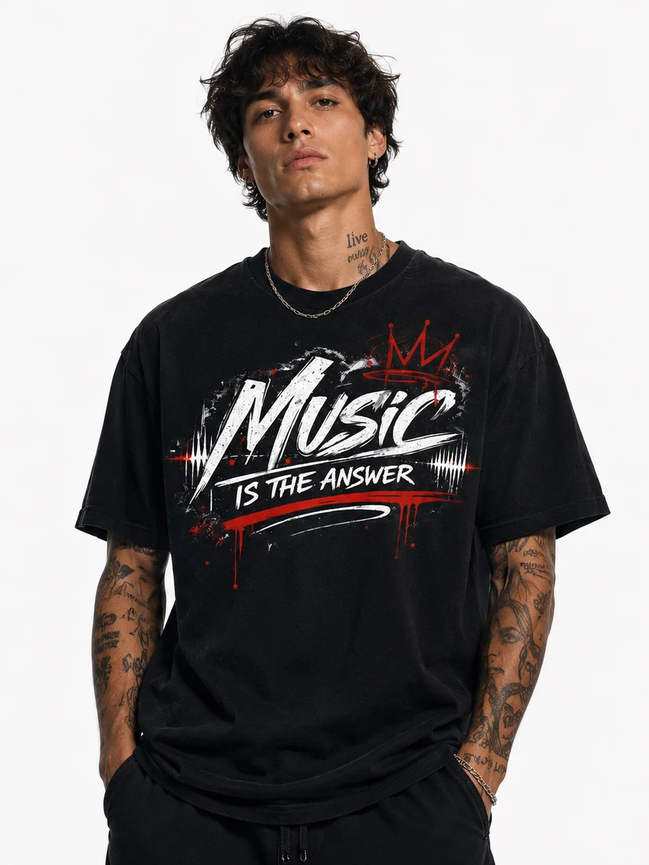 Man with tattoos wearing black shirt that says 'Music is the answer' in bold white and red text.