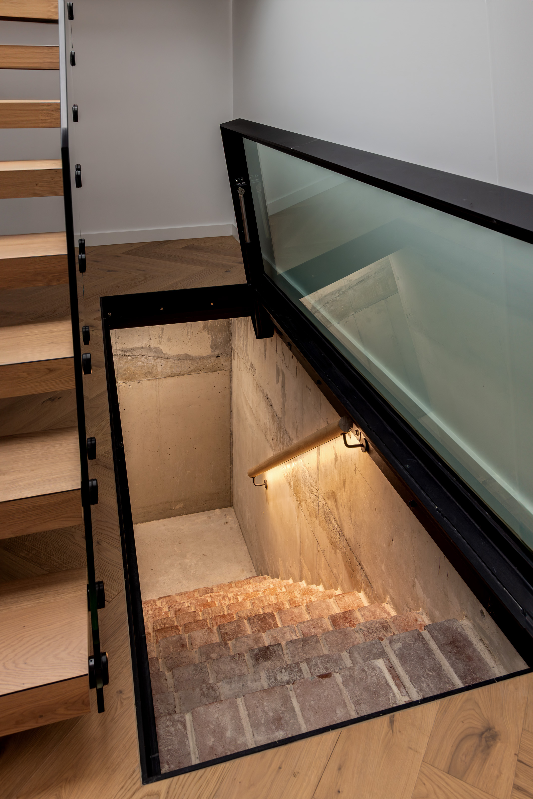 Original brick cellar staircase revealed beneath a glass floor beside the new timber stair at 54 North Adelaide