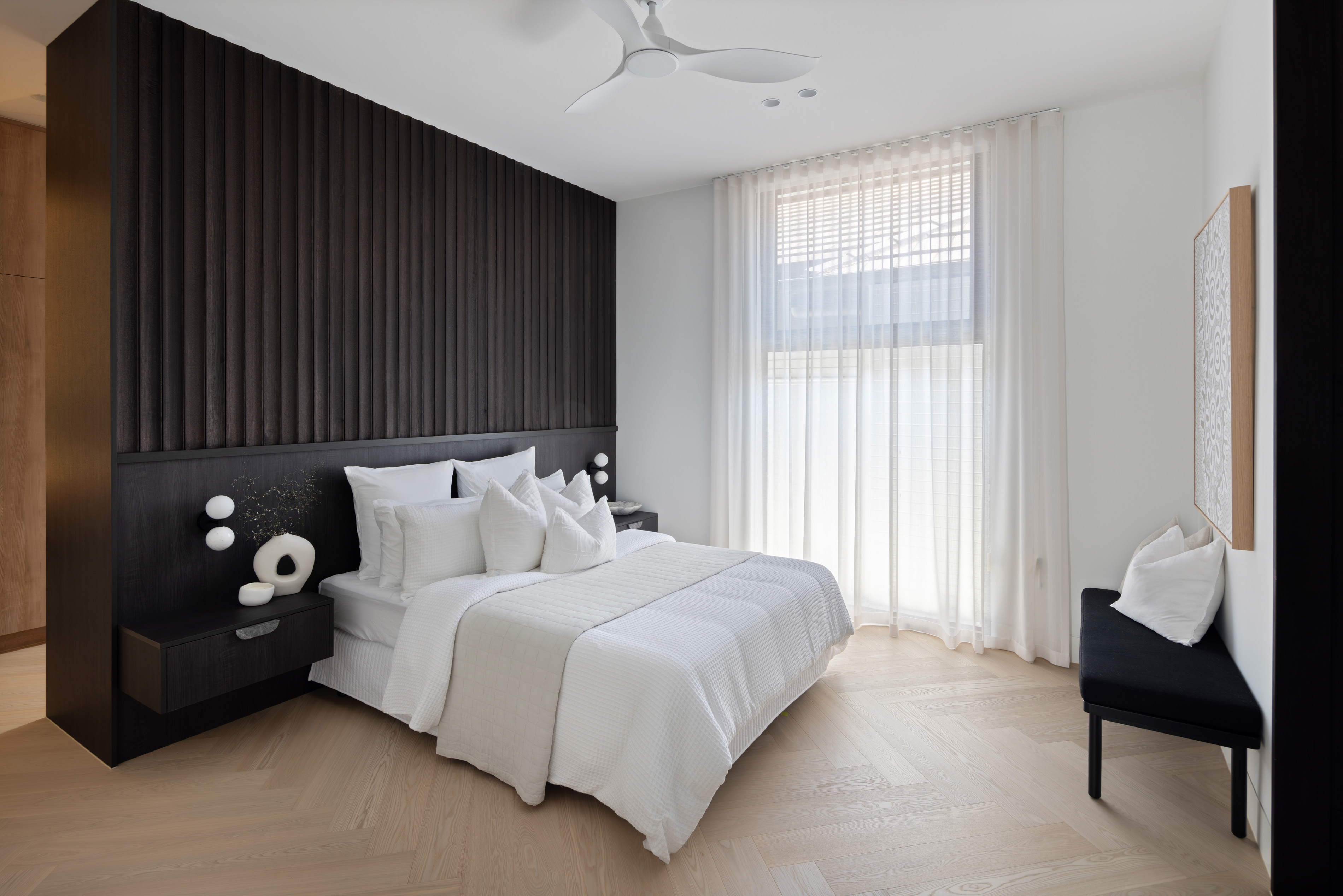 Main bedroom with dark timber battened feature wall and sheer curtains at 9 Netherby