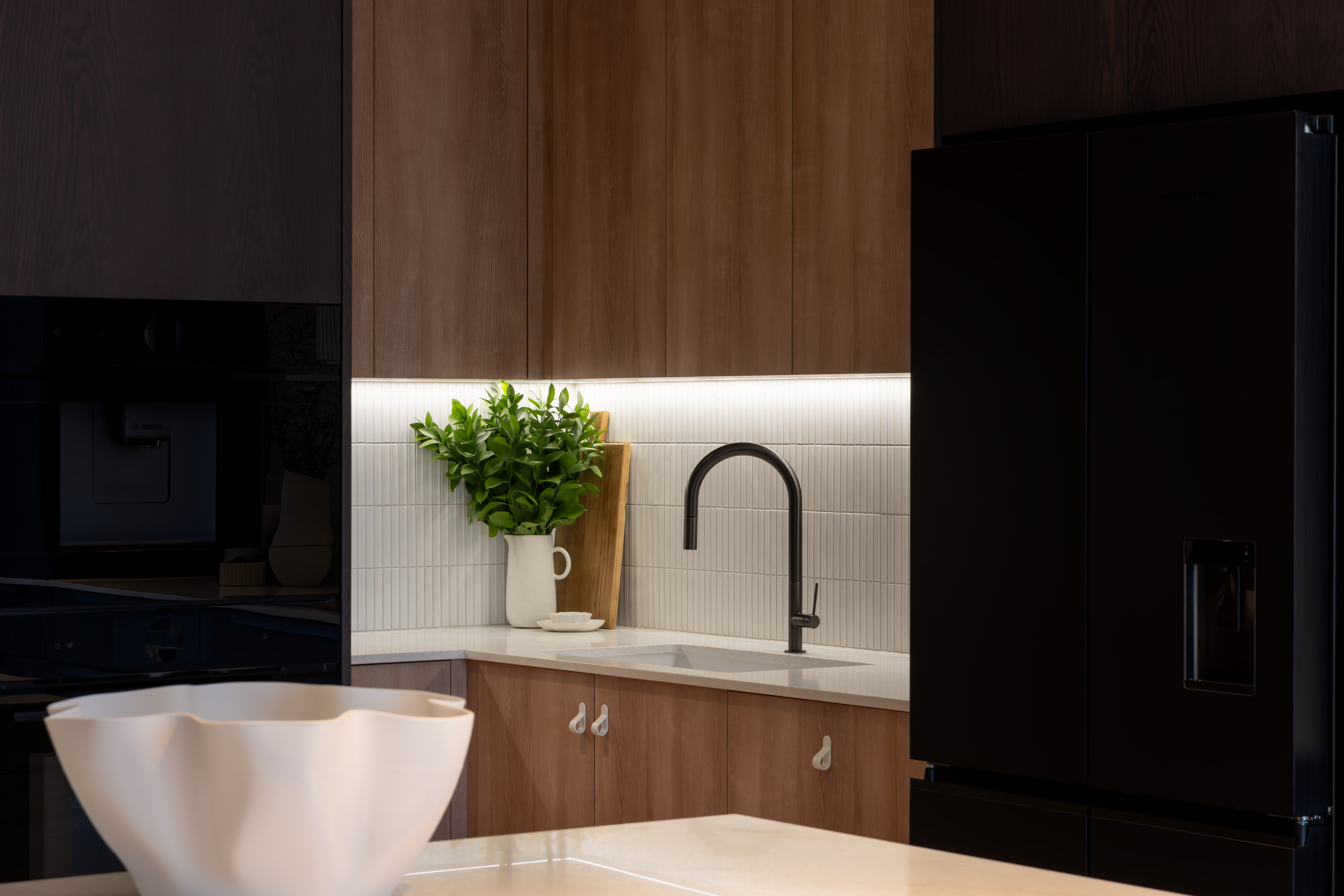 Kitchen corner with timber cabinetry, white tiled splashback and matte black tapware